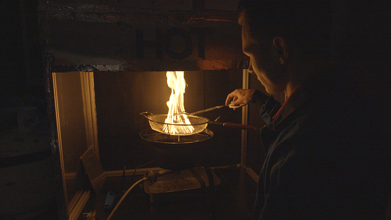 Joe Alascio, a graduate student in fire protection engineering, tends to a pile of burning embers called "firebrands" as part of research to prevent the embers from starting fires miles from the fire line.