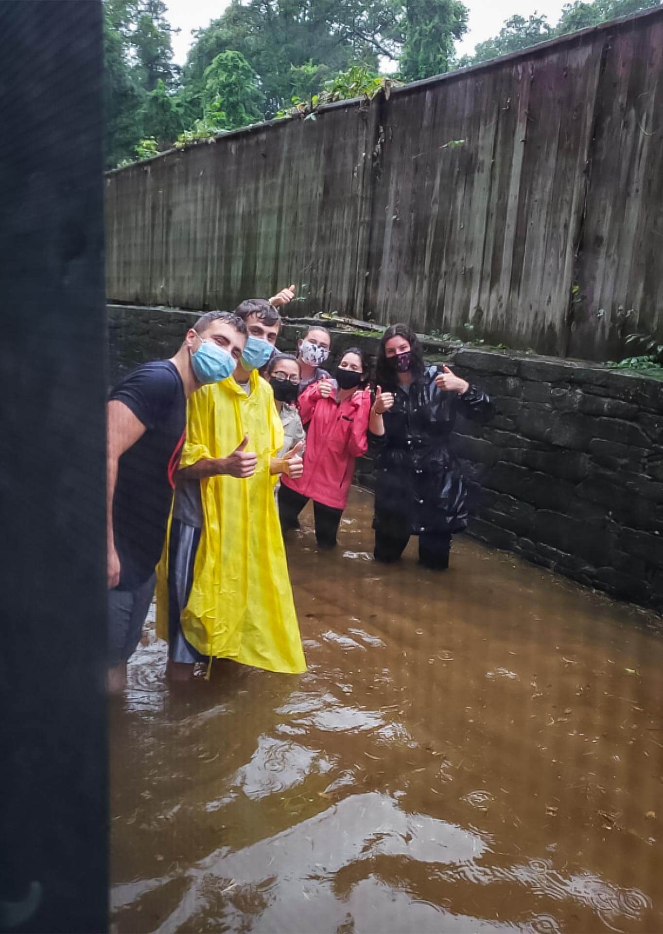 Masked students stand in flood water