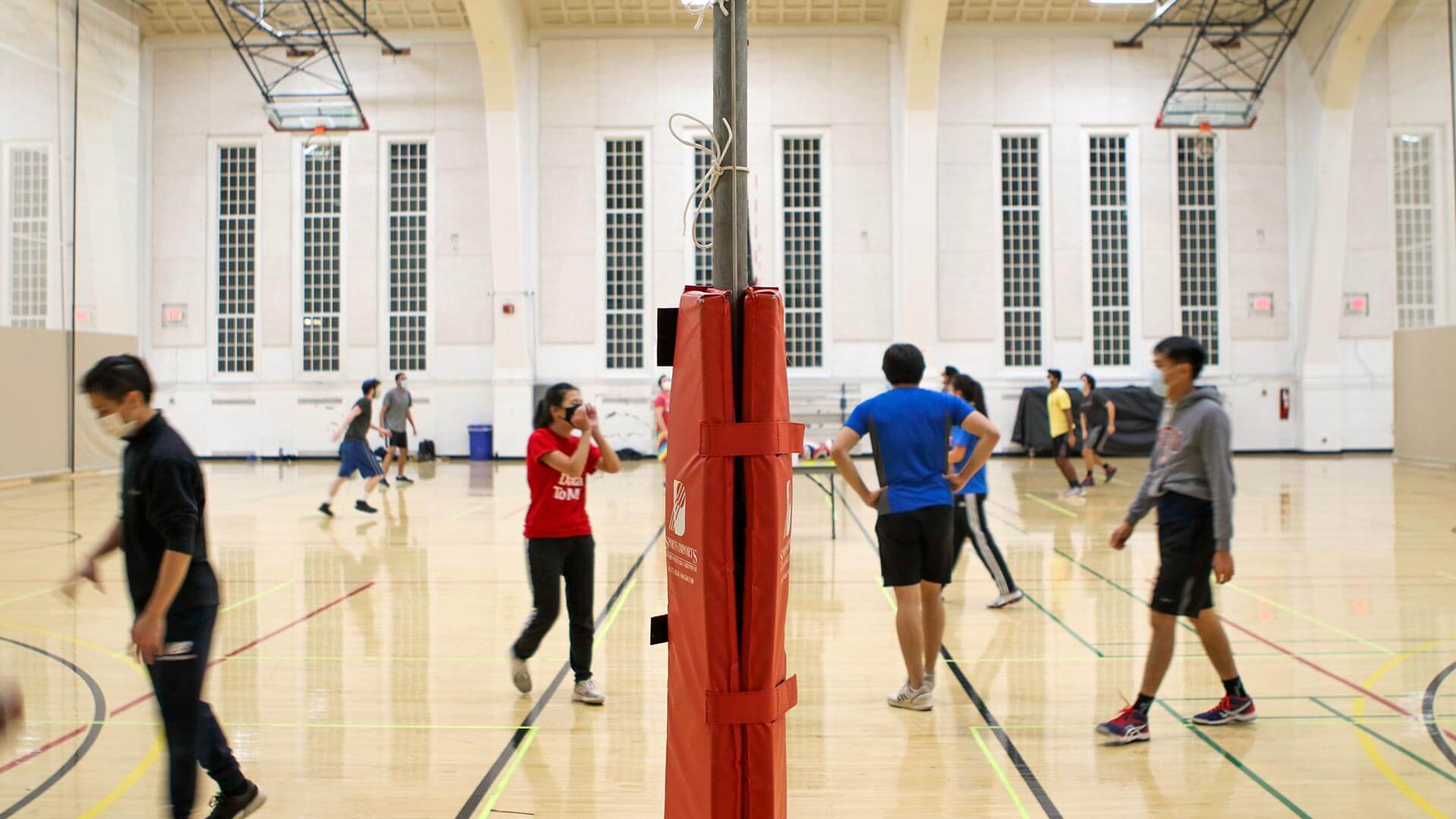Students wearing masks play intramural volleyball