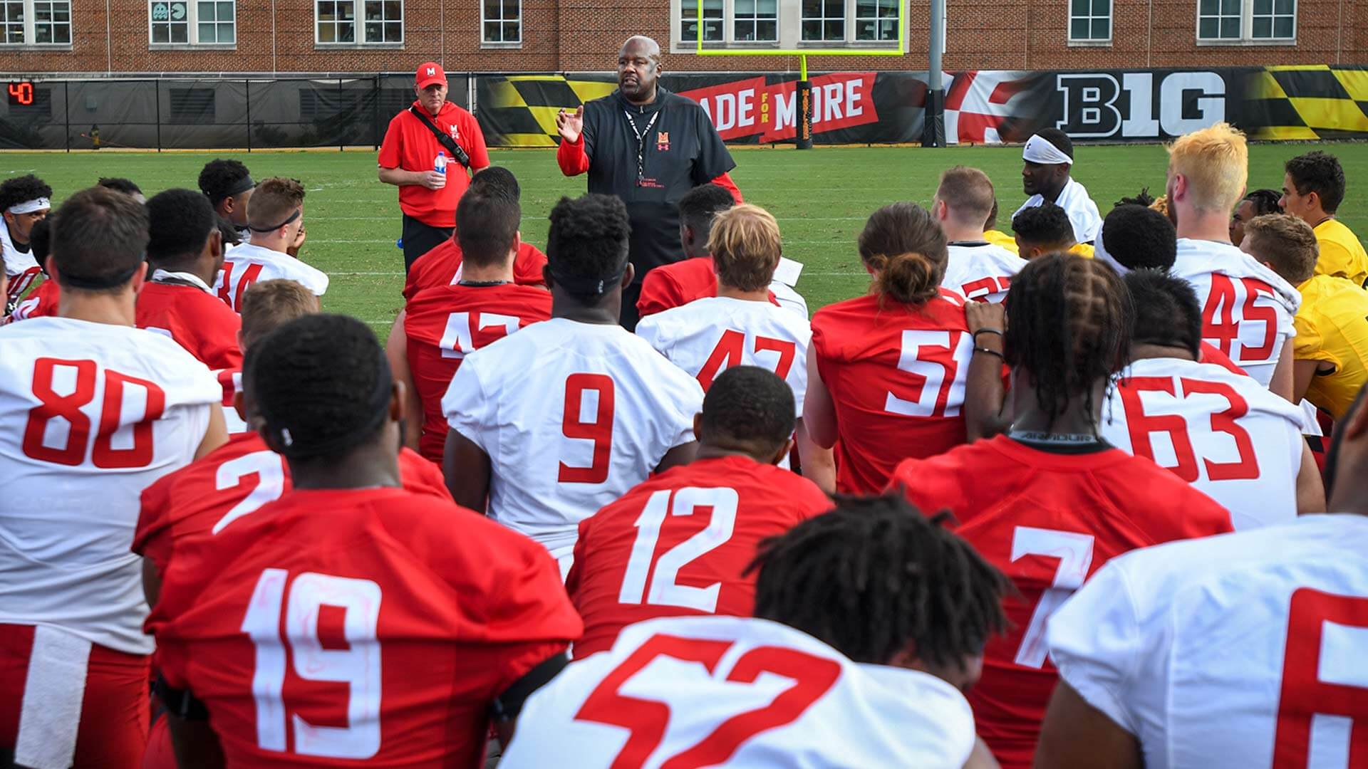 Head Coach Michael Locksley speaks to football players at practice
