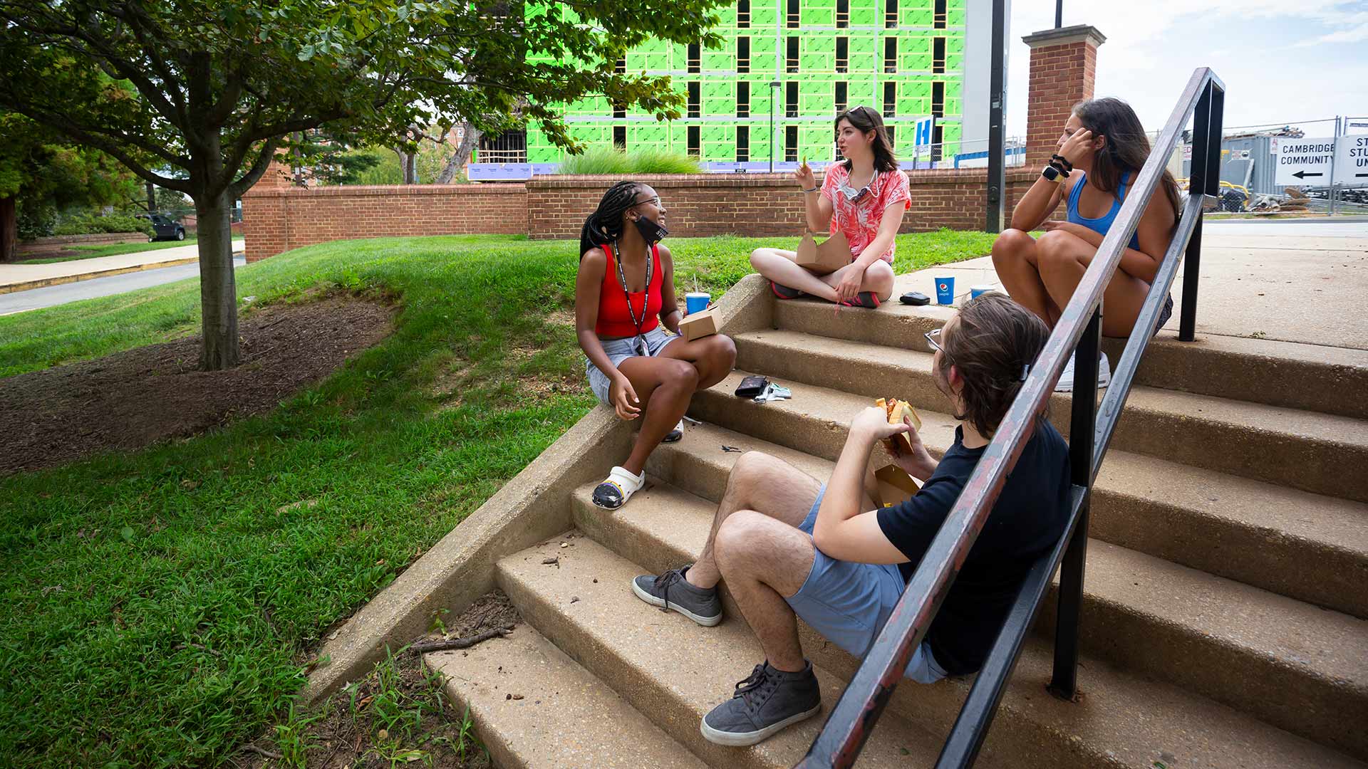 Students sit and eat on stairs outside