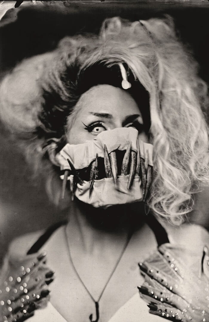Woman wears mask with large fangs